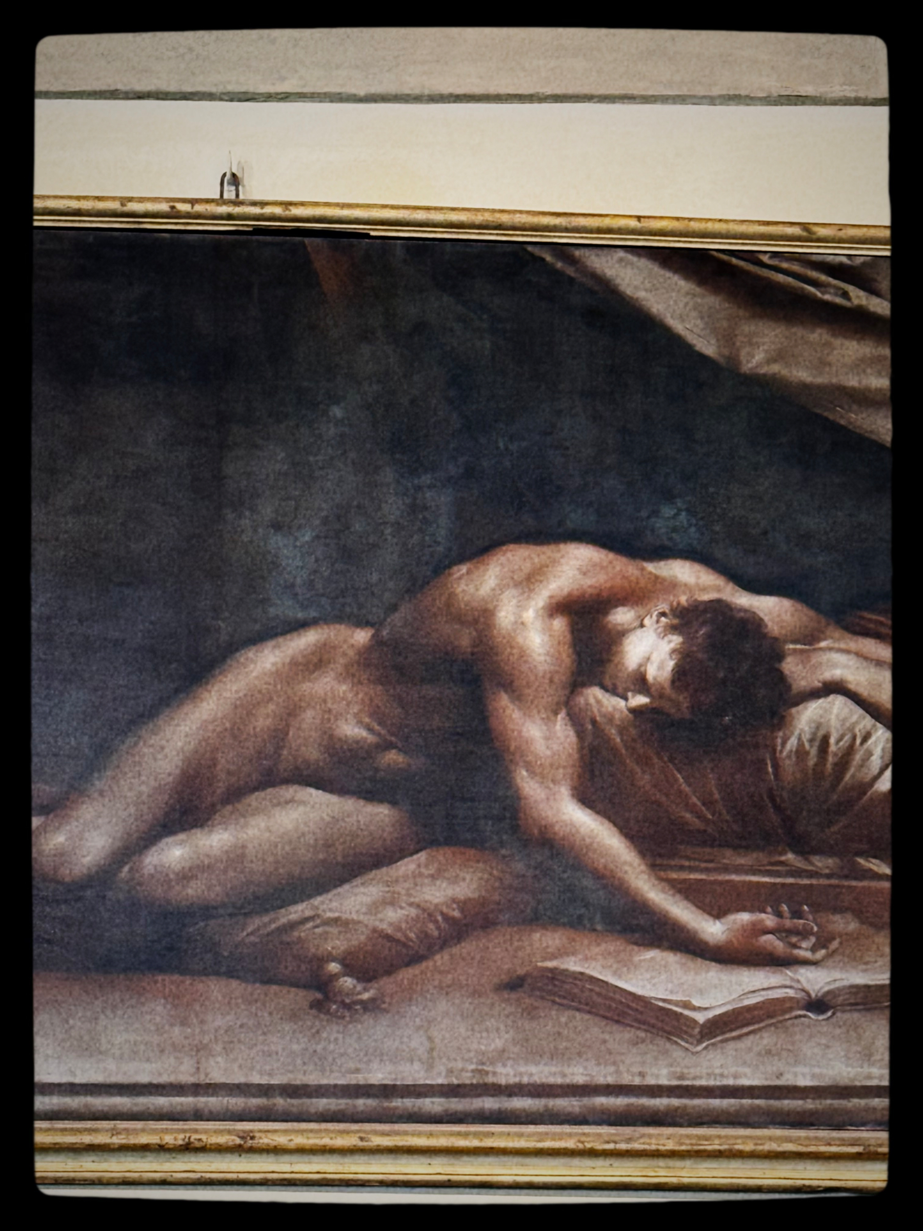 A person is depicted lying prone on a bed, with an open book nearby, in a painting with dark, muted tones.